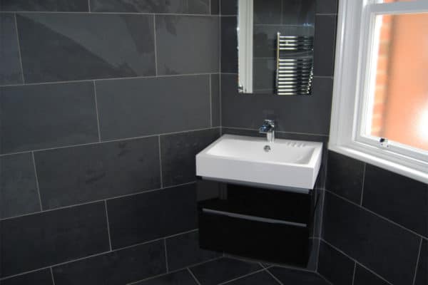 slate tiled bathroom with a wall hung basin & unit in gloss black