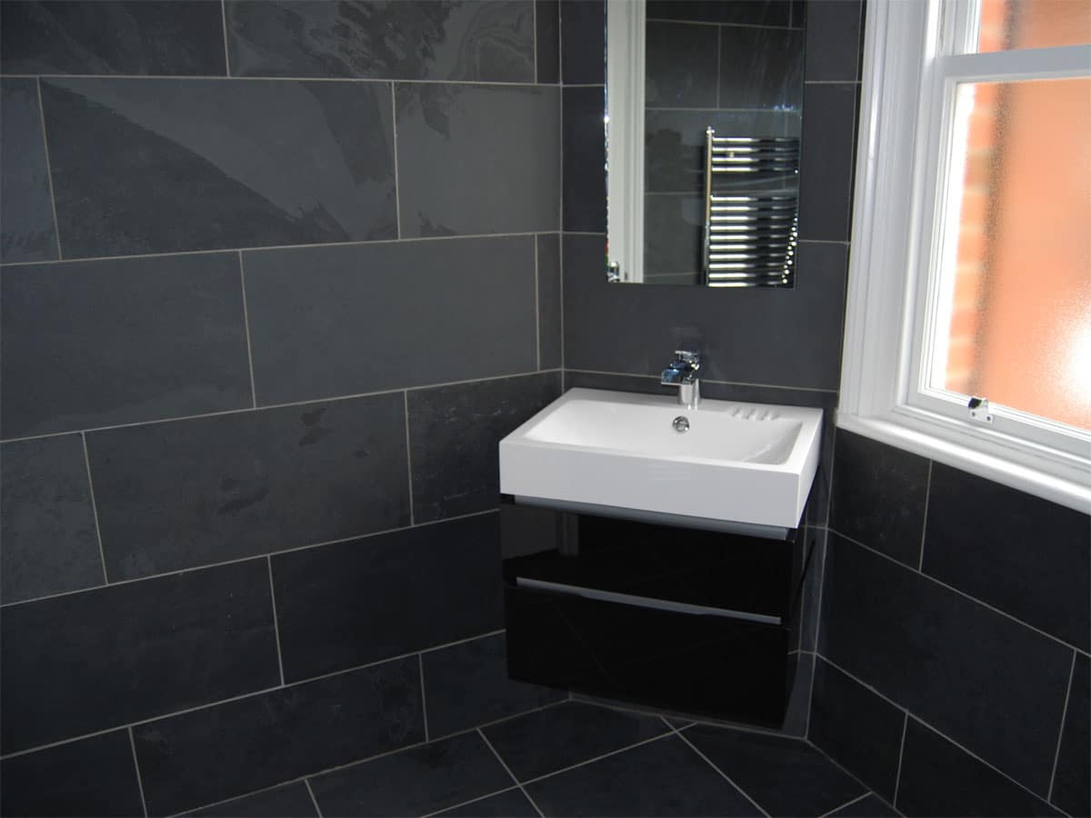 slate tiled bathroom with a wall hung basin & unit in gloss black