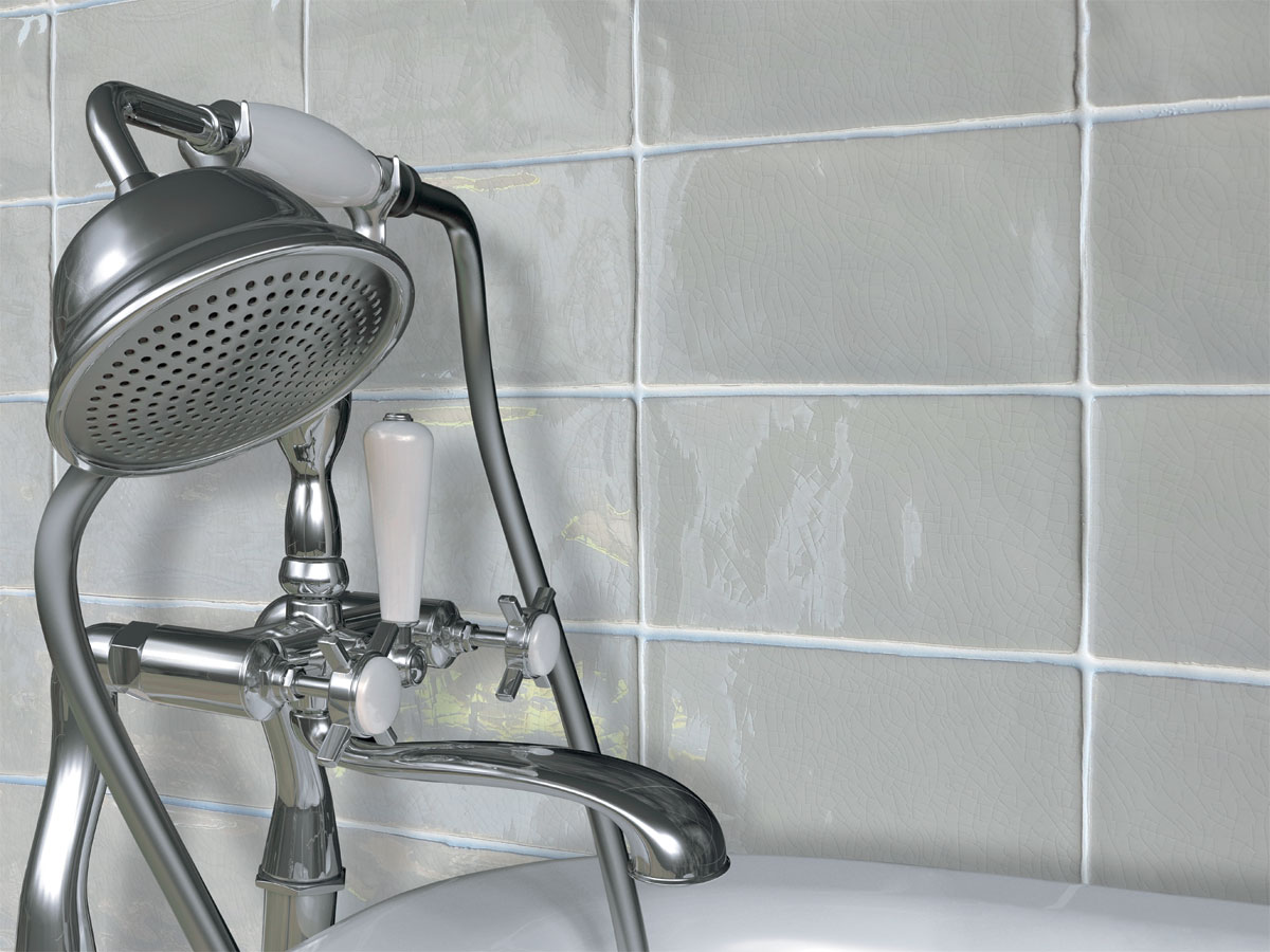 up close of a traditional bath tap with crackle tiles behind