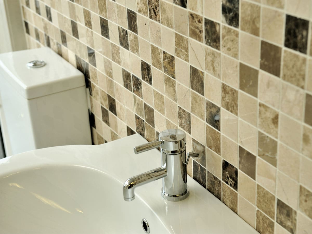 a marble mosaic wall with a basin & toilet in front