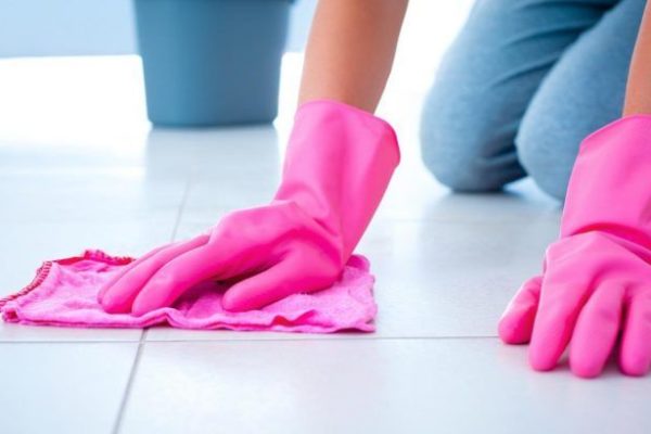 tiles being cleaned with a pink cloth and pink rubber gloves